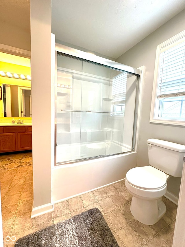 bathroom featuring vanity, shower / bath combination with glass door, toilet, and baseboards