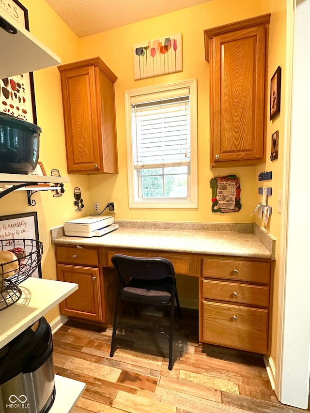 kitchen featuring light wood-style flooring, brown cabinets, and light countertops