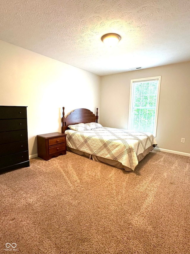 carpeted bedroom featuring a textured ceiling and baseboards