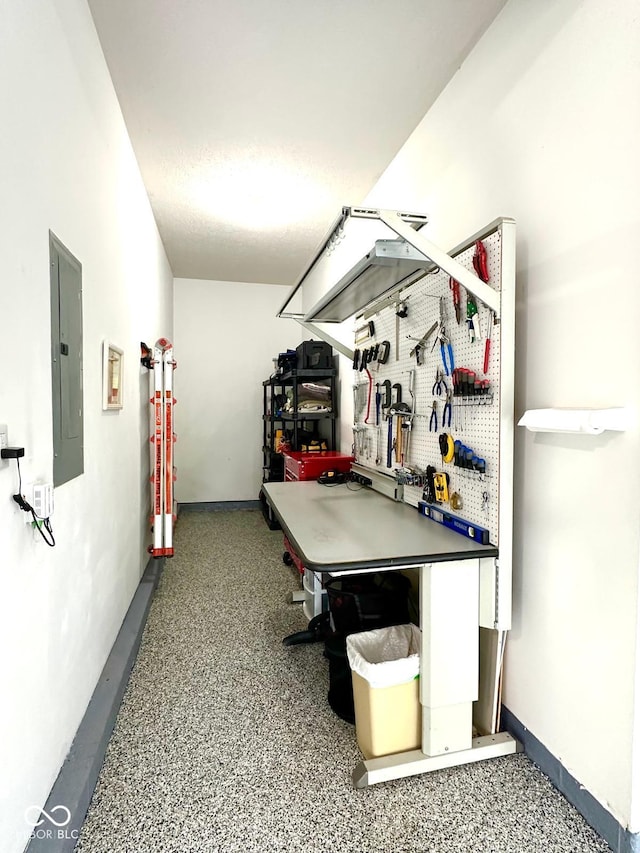game room with a workshop area, electric panel, and speckled floor