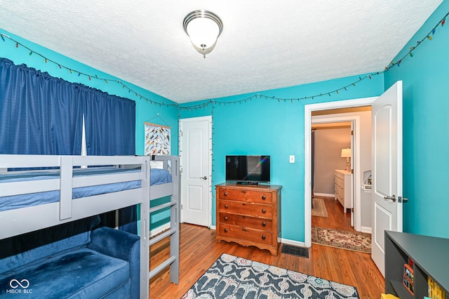 bedroom with a textured ceiling and wood finished floors