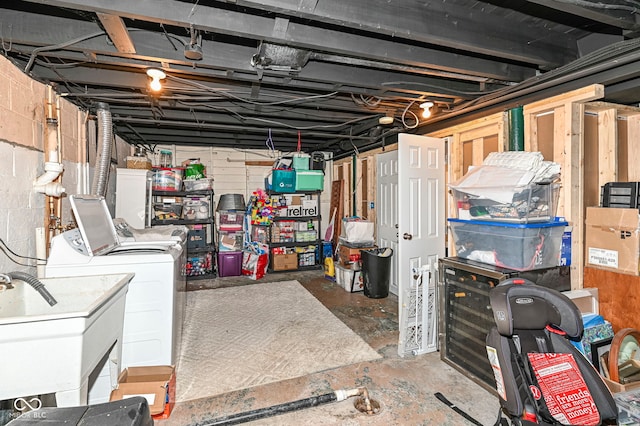 unfinished basement with a sink, concrete block wall, and washing machine and clothes dryer