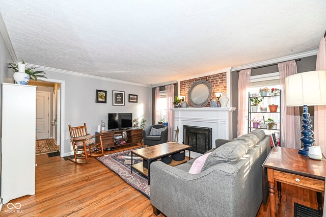 living room with crown molding, a fireplace, a textured ceiling, light wood-type flooring, and visible vents