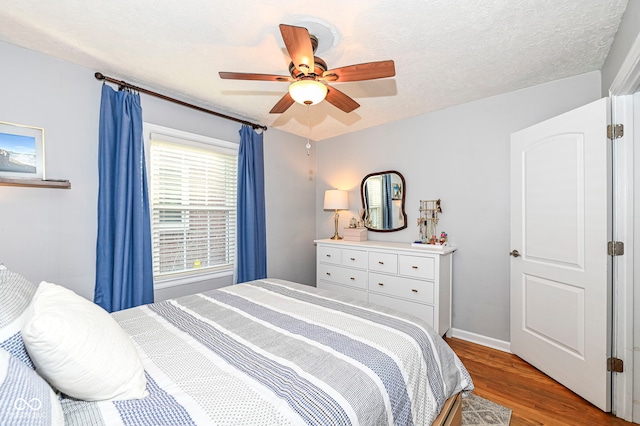 bedroom with baseboards, ceiling fan, a textured ceiling, and wood finished floors