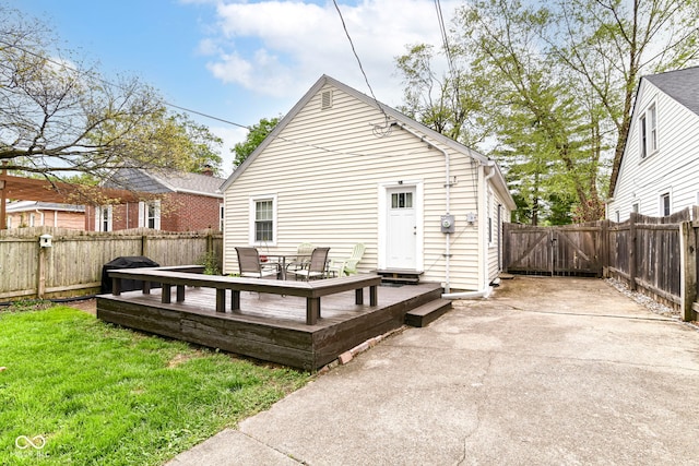 rear view of house with a yard, a deck, a gate, and a fenced backyard
