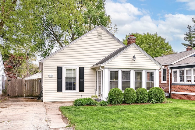 view of front of home with fence, a chimney, and a front lawn