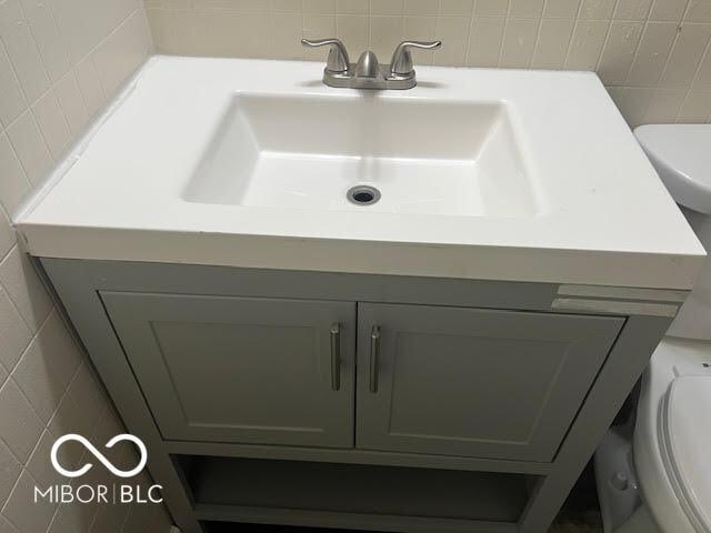 1204 Ladoga Rd, Crawfordsville, IN 47933 - half bath featuring vanity, toilet, backsplash, and tile walls