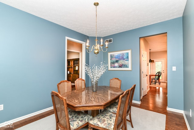 dining area featuring baseboards, visible vents, dark wood-style flooring, and a notable chandelier