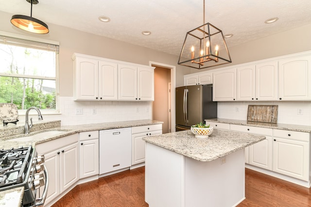 kitchen with dark wood-style flooring, stainless steel appliances, white cabinetry, and a sink