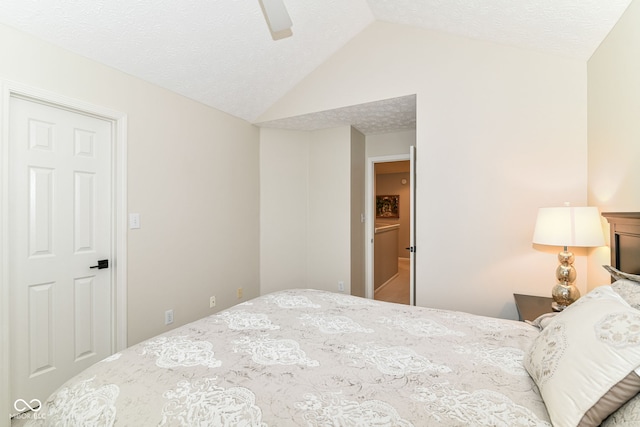 bedroom with a textured ceiling, ceiling fan, and vaulted ceiling