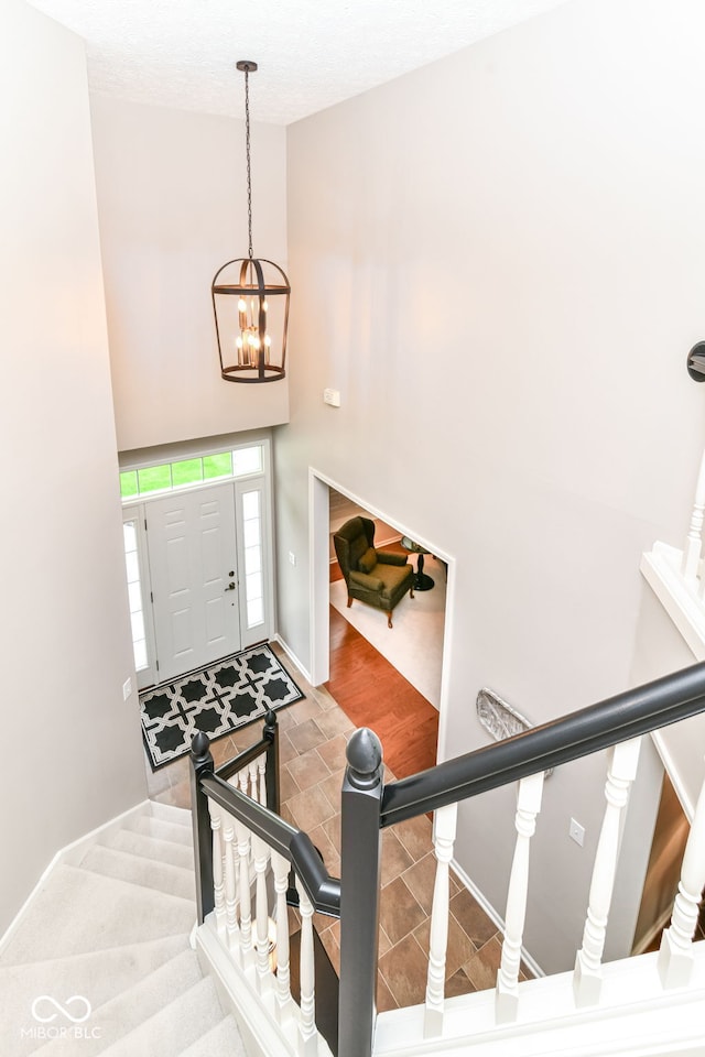 entrance foyer featuring an inviting chandelier, stairs, baseboards, and high vaulted ceiling