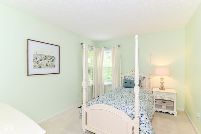 bedroom featuring a textured ceiling, baseboards, and light carpet