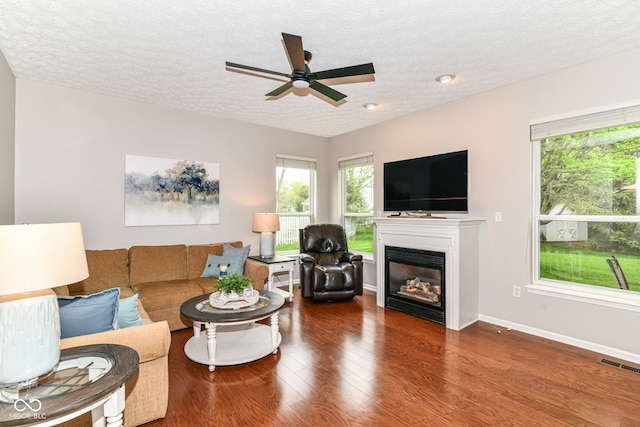 living room with a textured ceiling, visible vents, plenty of natural light, and wood finished floors