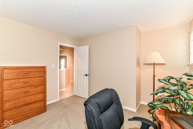 office featuring baseboards, a textured ceiling, and light carpet