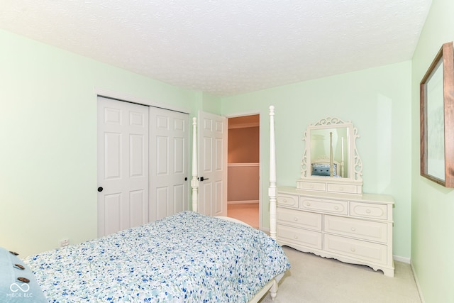 bedroom with baseboards, a closet, a textured ceiling, and light colored carpet