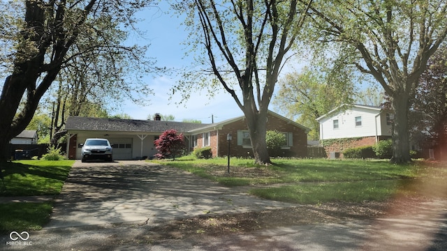 view of front of house featuring driveway, a front yard, and brick siding