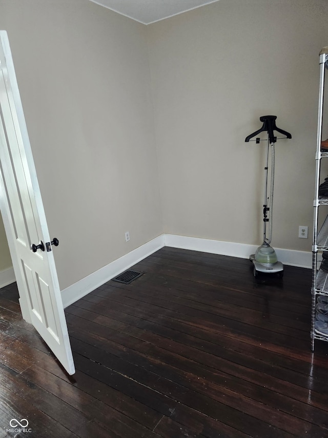 interior space with dark wood-type flooring, baseboards, and visible vents