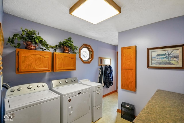 laundry area featuring a textured ceiling, light colored carpet, washing machine and clothes dryer, cabinet space, and baseboards