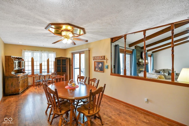 dining space with lofted ceiling with beams, a textured ceiling, ceiling fan, and wood finished floors