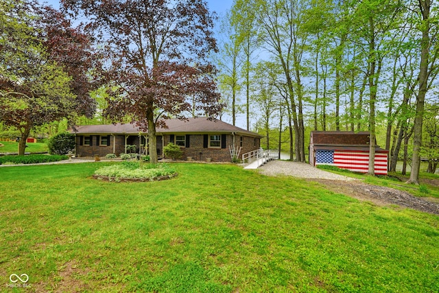 view of front of home featuring an outdoor structure, driveway, a front lawn, and brick siding