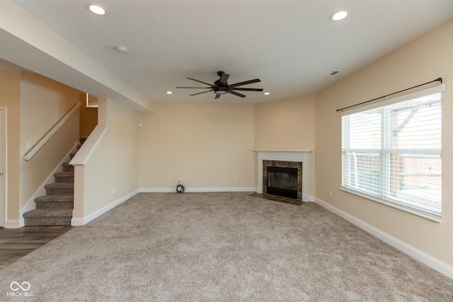 unfurnished living room featuring a ceiling fan, carpet, recessed lighting, stairway, and a tiled fireplace