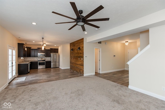 unfurnished living room featuring carpet flooring, recessed lighting, a ceiling fan, baseboards, and a sink
