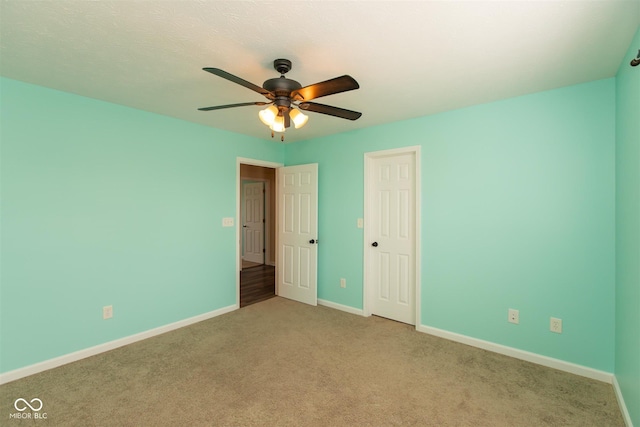 unfurnished bedroom featuring carpet floors, baseboards, a closet, and a ceiling fan