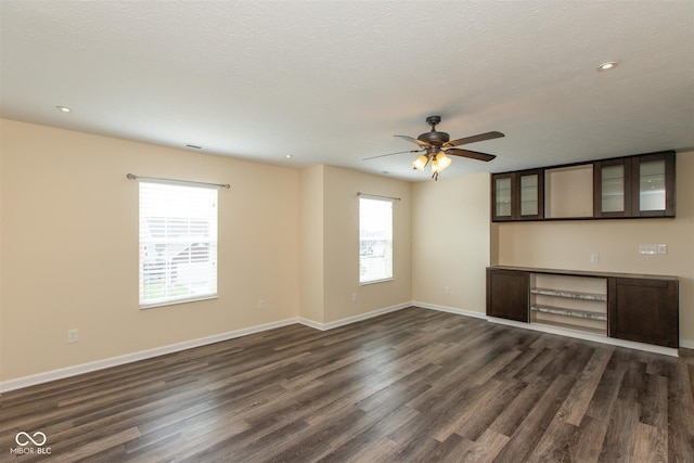 unfurnished living room with healthy amount of natural light, dark wood-style floors, a ceiling fan, recessed lighting, and a textured ceiling