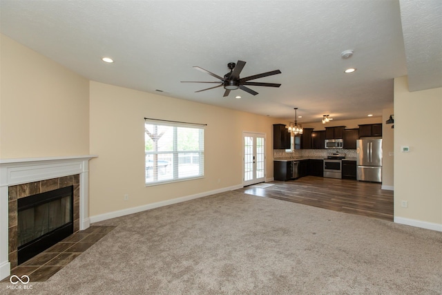 unfurnished living room featuring dark carpet, ceiling fan, recessed lighting, a tile fireplace, and baseboards