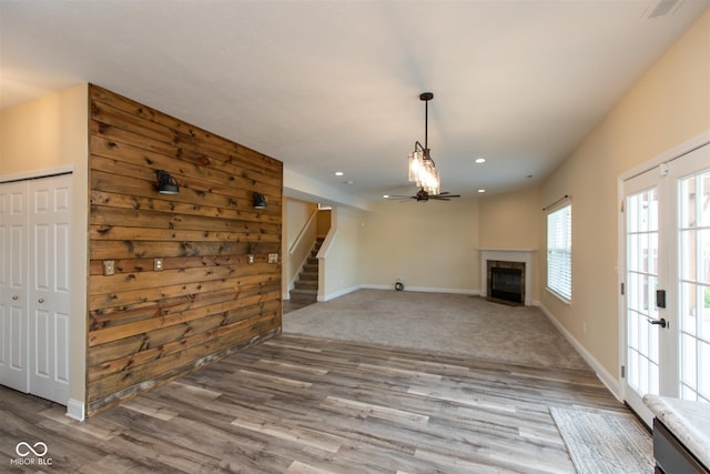 unfurnished living room with wood finished floors, baseboards, recessed lighting, stairs, and a fireplace with flush hearth