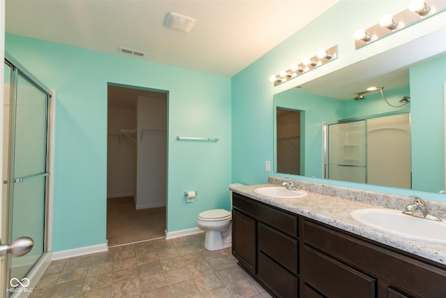 full bathroom featuring a shower stall, baseboards, toilet, and double vanity