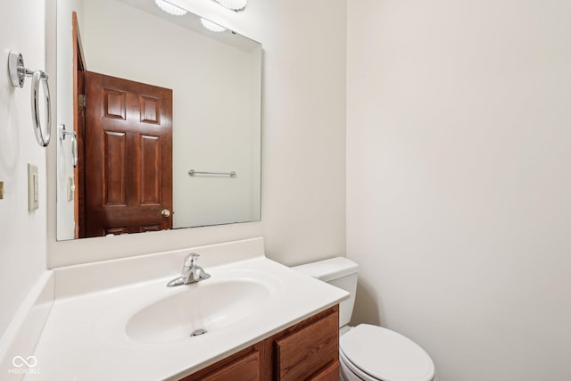 half bath featuring vanity and toilet