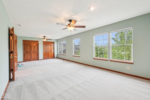 spare room with light colored carpet, baseboards, ceiling fan, a textured ceiling, and a smoke detector