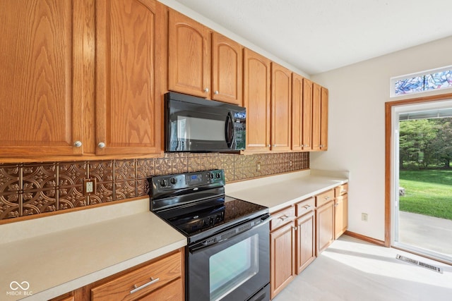 kitchen featuring black appliances, decorative backsplash, light countertops, and baseboards