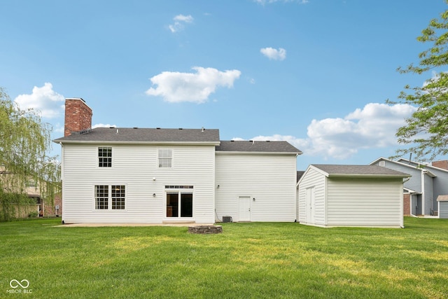 back of house with a lawn, a chimney, an outbuilding, a fire pit, and a shed