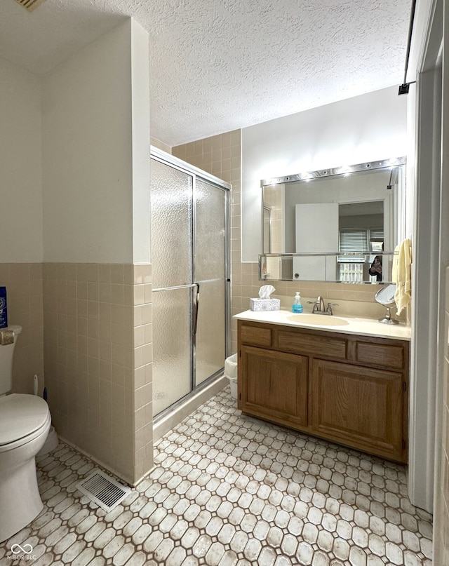 4212 Foxglove Trce, Indianapolis, IN 46237 - bathroom featuring toilet, tile walls, vanity, a shower stall, and a textured ceiling