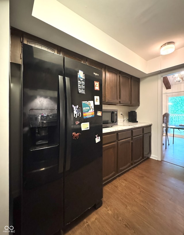 4212 Foxglove Trce, Indianapolis, IN 46237 - kitchen with black refrigerator with ice dispenser, stainless steel microwave, light countertops, dark wood-style flooring, and dark brown cabinetry