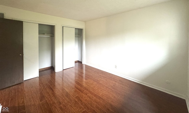 4212 Foxglove Trce, Indianapolis, IN 46237 - unfurnished bedroom with dark wood finished floors, baseboards, and multiple closets