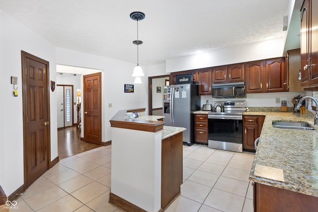 kitchen featuring appliances with stainless steel finishes, hanging light fixtures, a sink, a center island, and light tile patterned floors