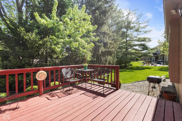wooden deck featuring a lawn and outdoor dining space