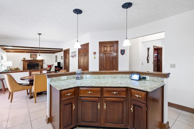 kitchen with hanging light fixtures, a fireplace, a textured ceiling, open floor plan, and light tile patterned floors
