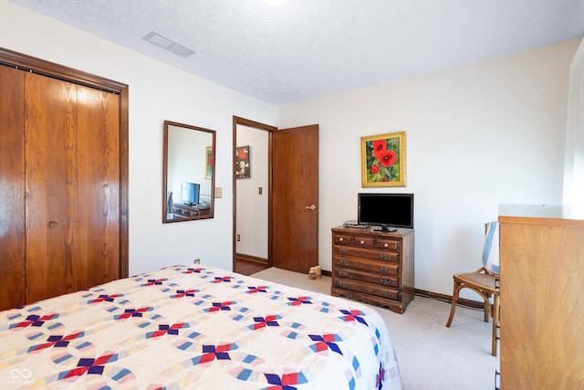 bedroom featuring a closet, a textured ceiling, visible vents, and light colored carpet