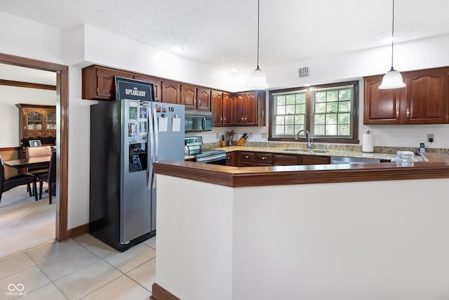 kitchen featuring hanging light fixtures, light tile patterned flooring, appliances with stainless steel finishes, and a sink
