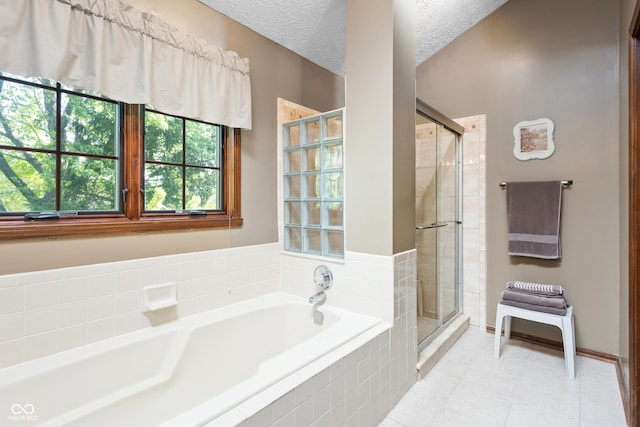 bathroom featuring a textured ceiling, tile patterned flooring, a garden tub, and a stall shower
