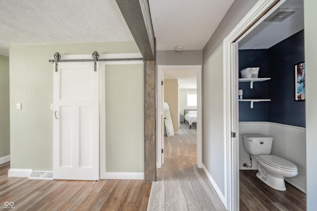bathroom featuring toilet, baseboards, visible vents, and wood finished floors
