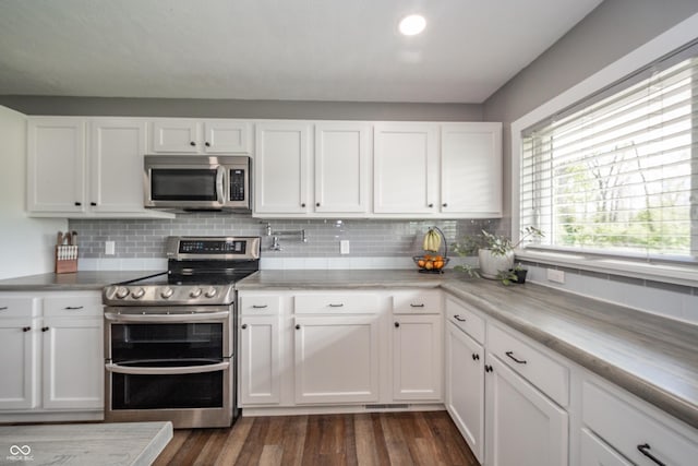 kitchen featuring backsplash, dark wood-style flooring, light countertops, white cabinets, and stainless steel appliances