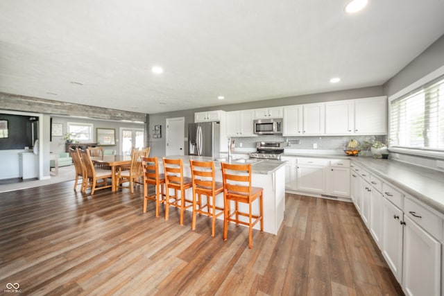 kitchen with appliances with stainless steel finishes, a breakfast bar, recessed lighting, and white cabinetry