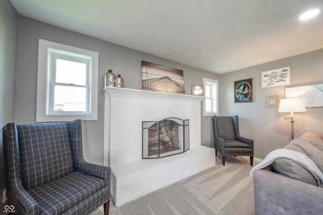 carpeted living area featuring a brick fireplace
