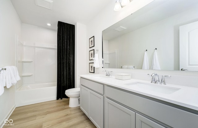 full bathroom featuring double vanity, toilet, wood finished floors, and a sink