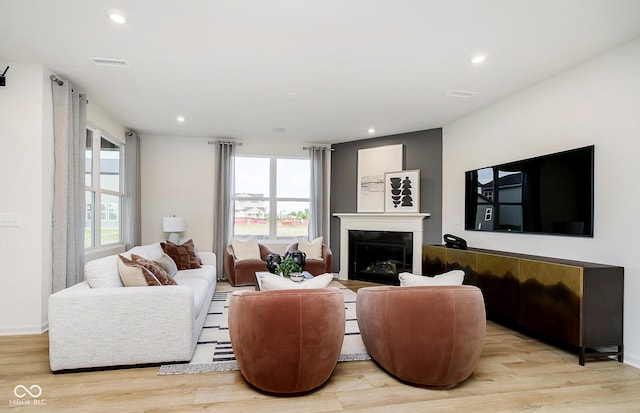 living room featuring light wood-type flooring, recessed lighting, a fireplace, and visible vents